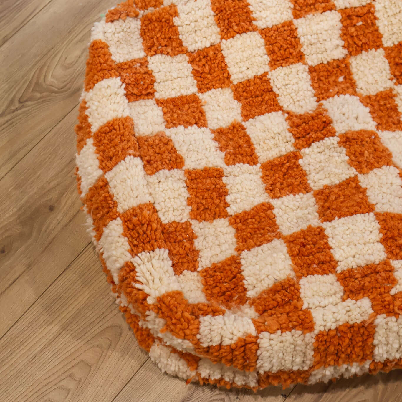 pouf Beni Ouarain damier orange sur un parquet en bois