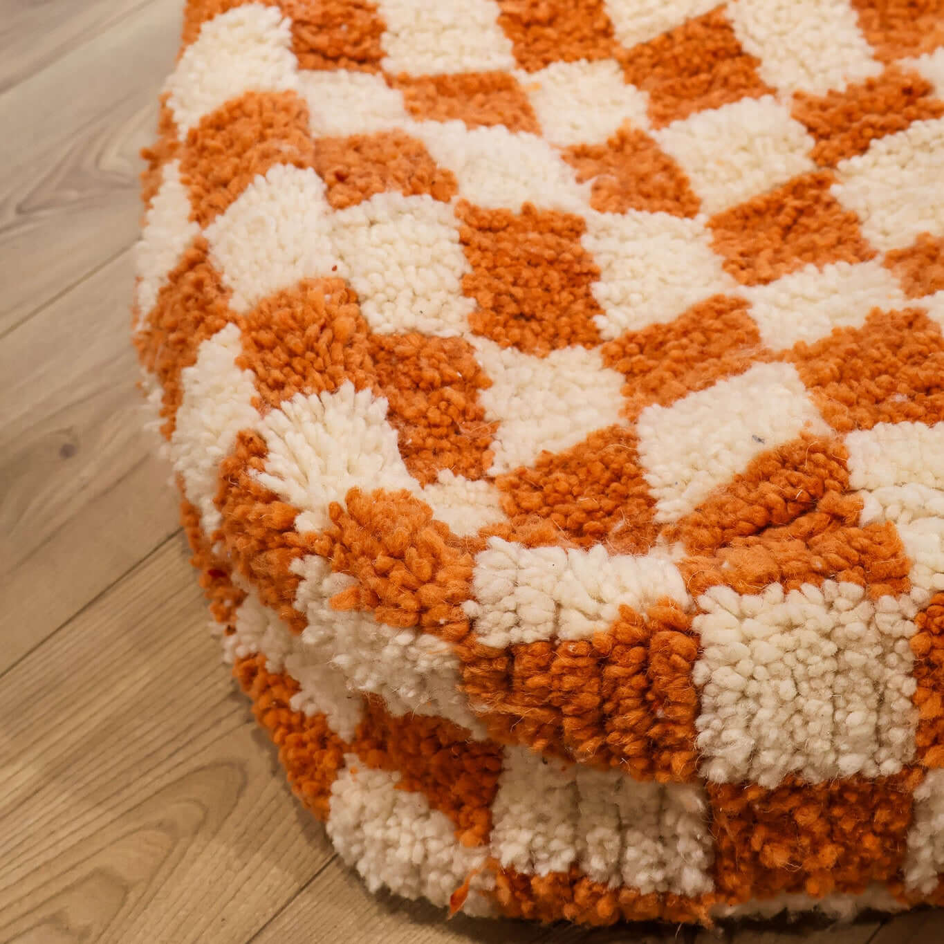 pouf Beni Ouarain damier orange sur un parquet en bois
