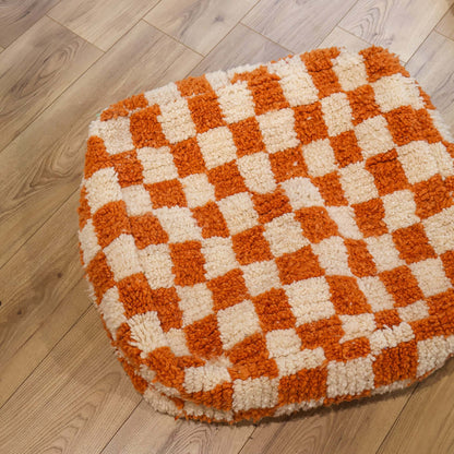 pouf Beni Ouarain damier orange sur un parquet en bois