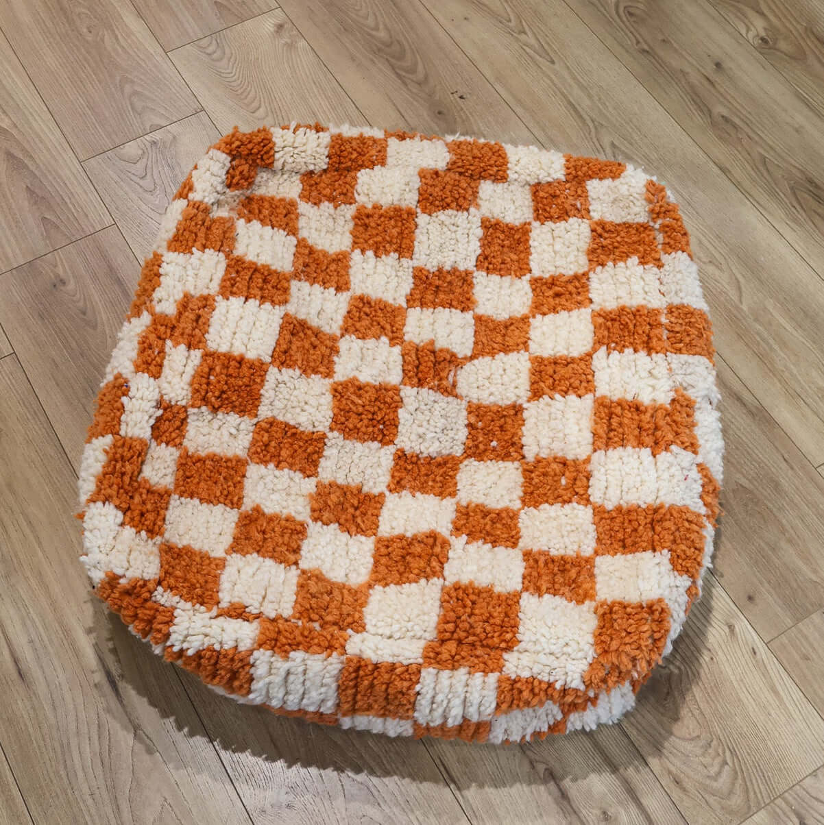 pouf Beni Ouarain damier orange sur un parquet en bois